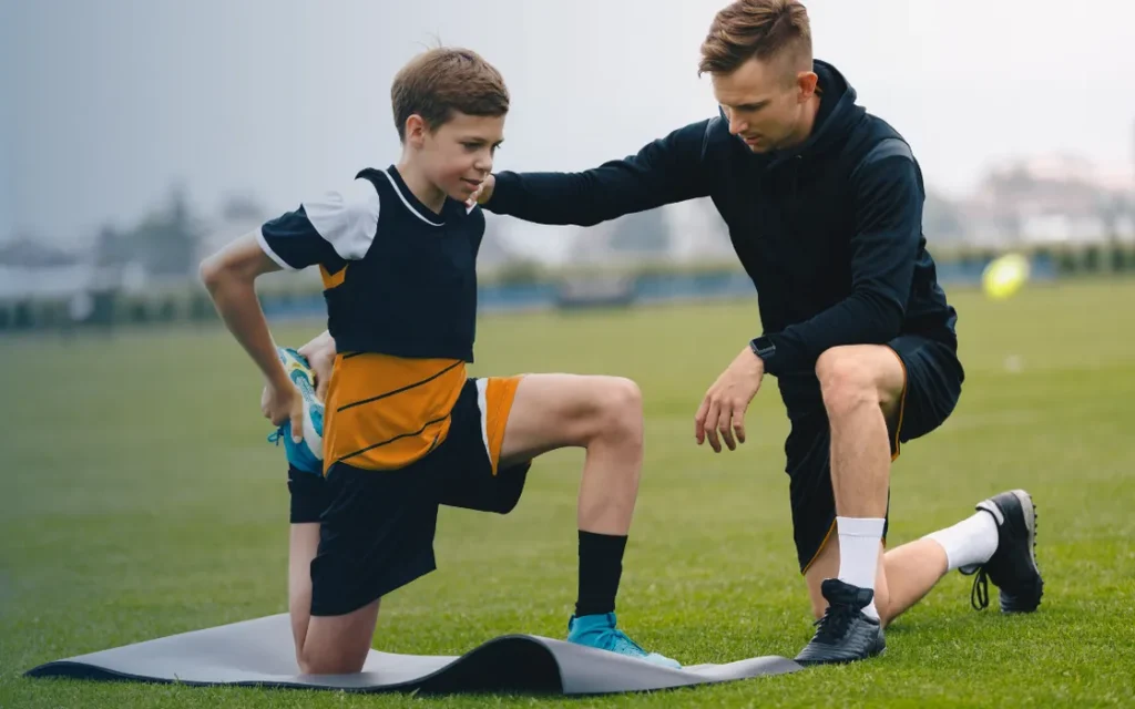 Coach working with a young athlete on a training field